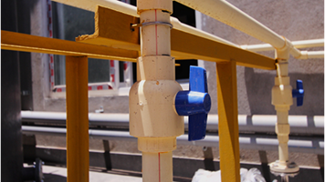 White PVC pipes with a blue-handled valve in a plumbing system