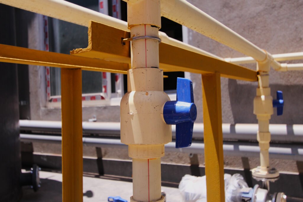 White PVC pipes with a blue-handled valve in a plumbing system