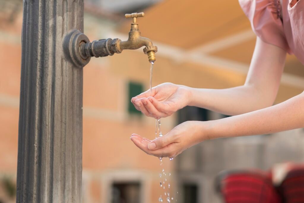 Young woman getting water from a faucet outdoors